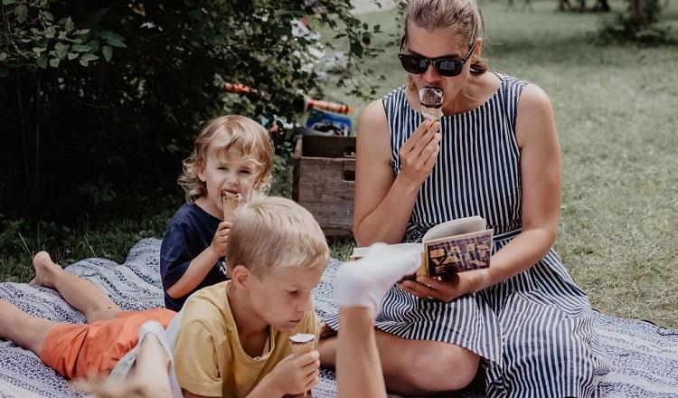 Textförfattaren och två barn sitter och läser och äter glass. Det är sommar.