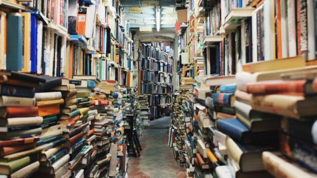 Massor med böcker i hyllor och i staplar.