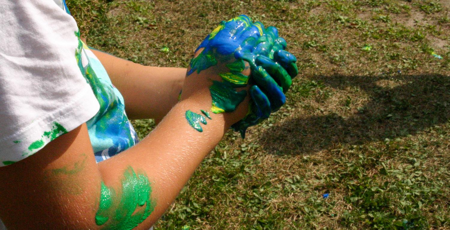 Barnhänder som är klottiga av modellera i granna turkosa och gröna färger.